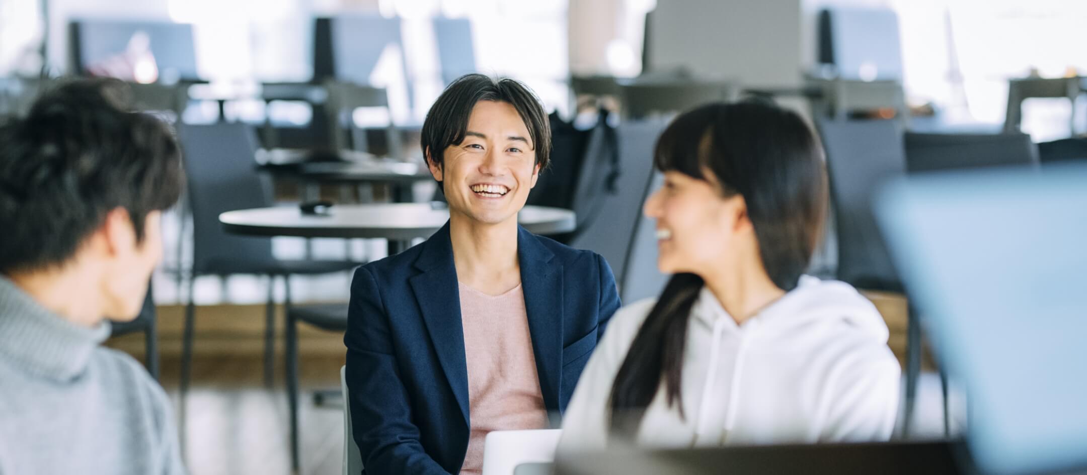 若い男性が仲間と座って喋りながら笑っている写真